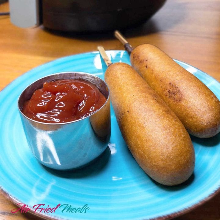 two corn dogs on a teal plate.