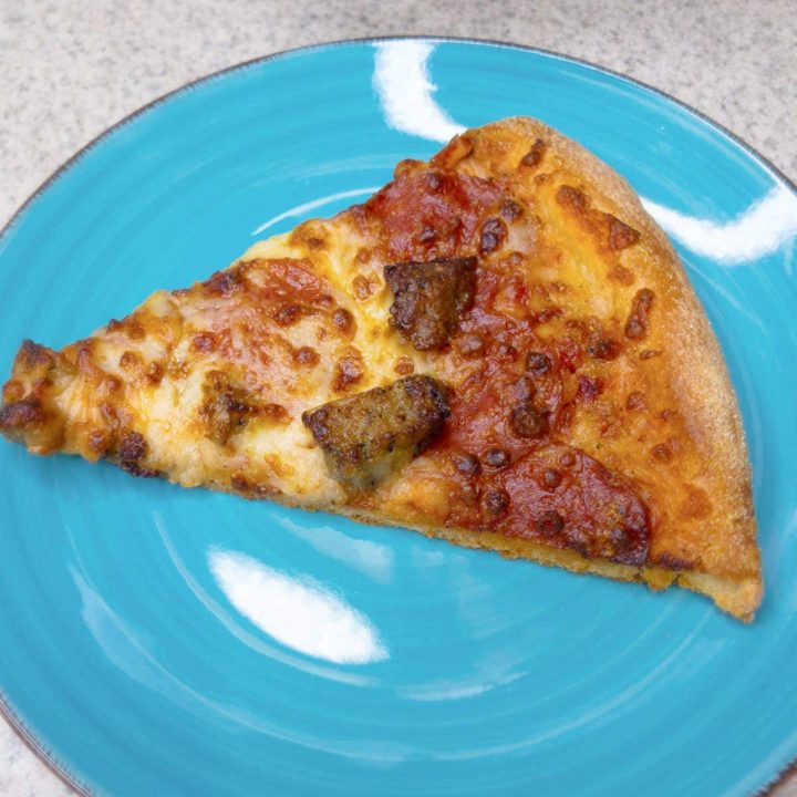 piece of pizza on a teal plate.