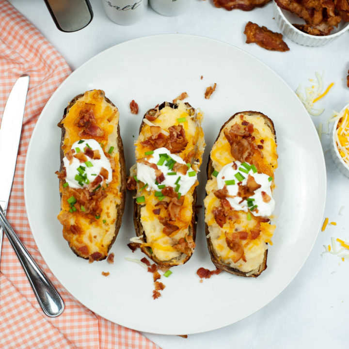 Top down view of three twice baked potatoes with sour cream, bacon, and chopped chives.