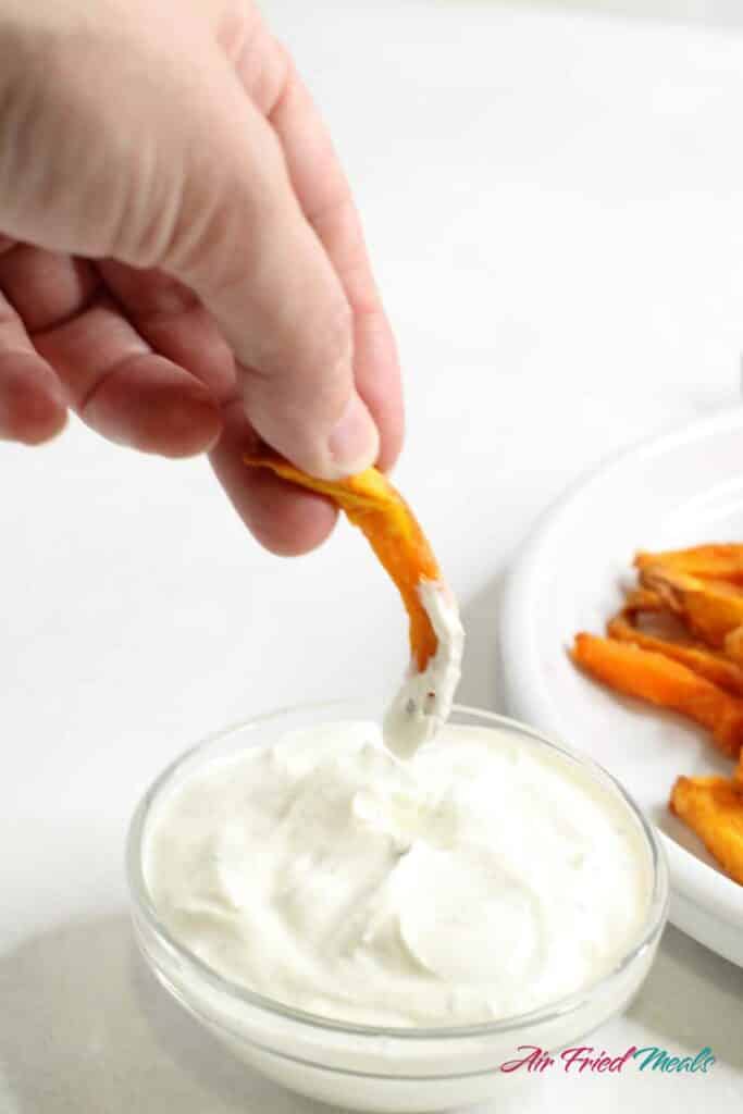 air fried frozen sweet potato fry being dipped in ranch.