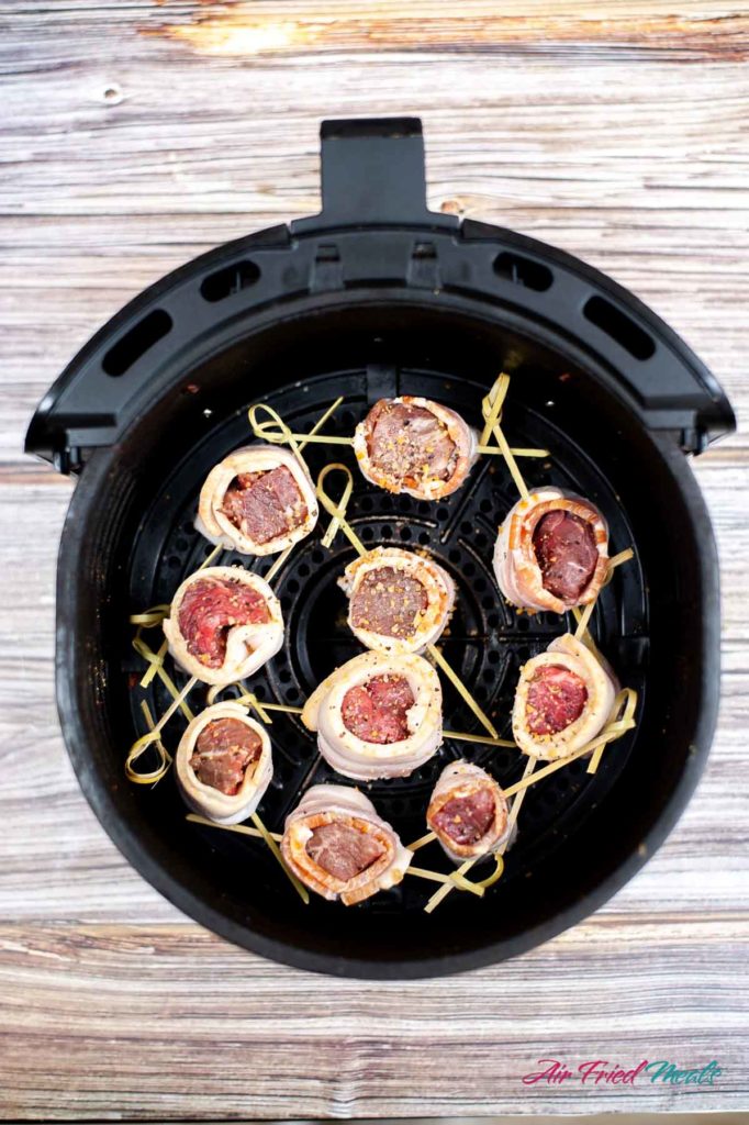 Top down of bacon wrapped steak in air fryer basket.