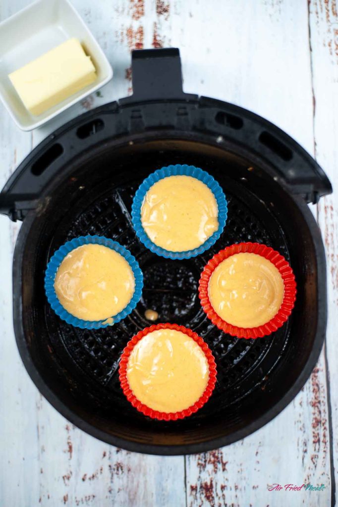 muffin batter in silicone muffin liners in air fryer basket.