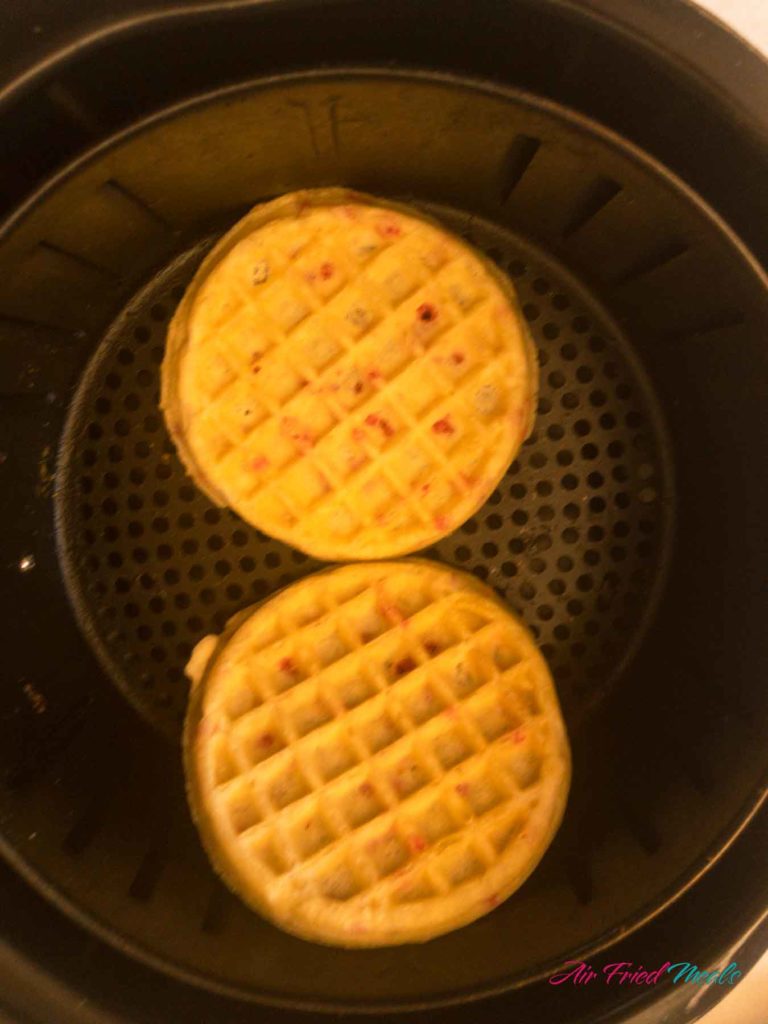 cooked waffles in air fryer basket.