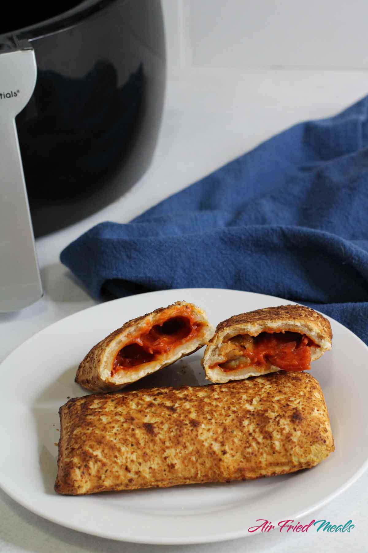 2 hot pockets on a plate, one cut in half and propped up against other hot pocket.